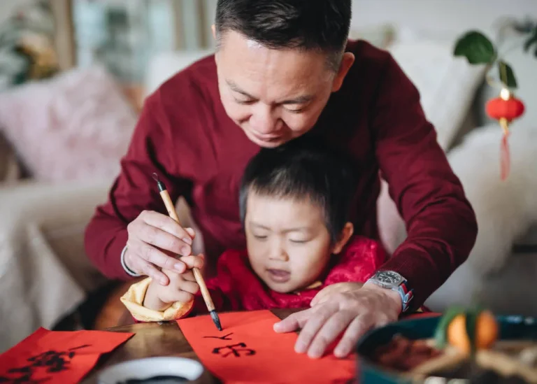 An adult helping a child practice Chinese writing.